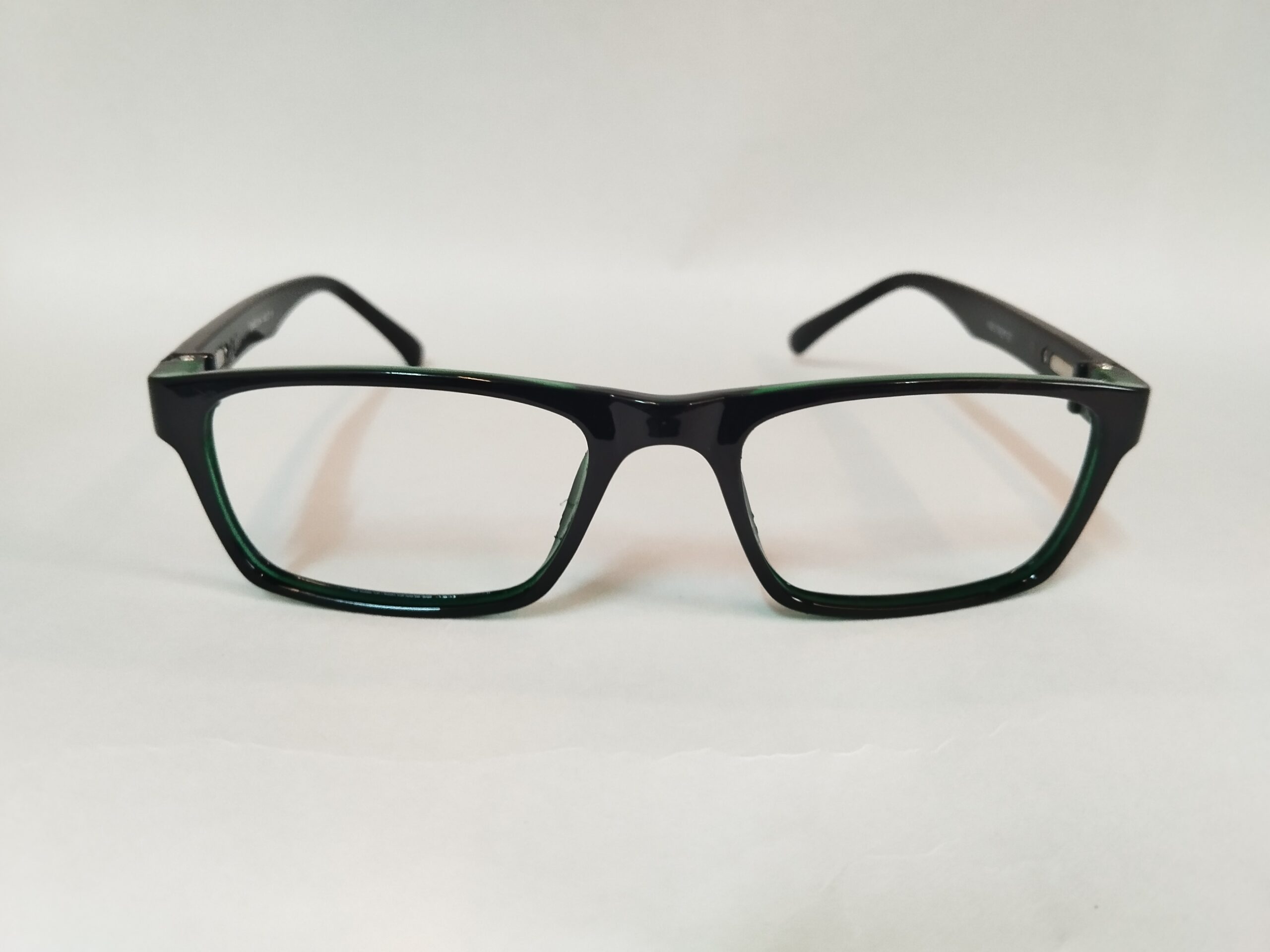 Glossy black eyeglasses frames with vibrant green accents, featuring a sleek and stylish two-tone design.